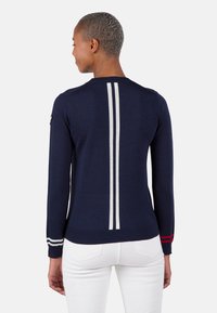 Marineblauer Pullover mit weißen vertikalen Streifen auf dem Rücken und gestreiften Akzenten an den Ärmeln. Strickmaterial, taillierte Passform, gerippter Saum.