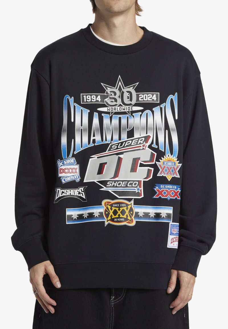 Black sweatshirt with graphic print featuring logos and text in white, blue, and red. Crew neck and long sleeves with a relaxed fit.