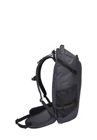 Zaino in tessuto nero con tasca laterale in rete, forma curva, spallacci imbottiti e hardware regolabile. Design semplice e funzionale.