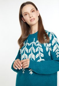 Pulover teal cu model de frunze albe, decolteu rotund și mâneci lungi. Textură moale și croială lejeră, cu manșete ribbate.