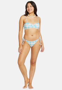 Dvivietis bikini, kuris pasižymi pastelinių spalvų languotu raštu. Viršus turi plonas juostas, o apačia su reguliuojamais raišteliais šonose.