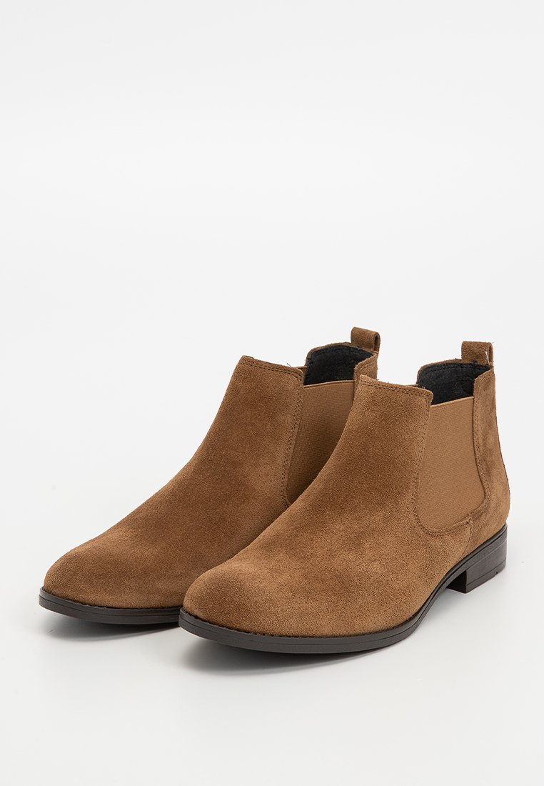 Ein Paar braune Wildleder-Chelsea-Stiefel mit elastischen Seitenpanels und niedrigen schwarzen Absätzen auf einem weißen Hintergrund.
