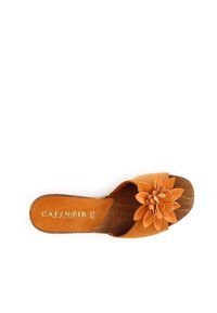 Sanda con tira de cuero marrón y un gran adorno de flor en capas en tonos más claros. Plantilla texturizada y logo de la marca visible.