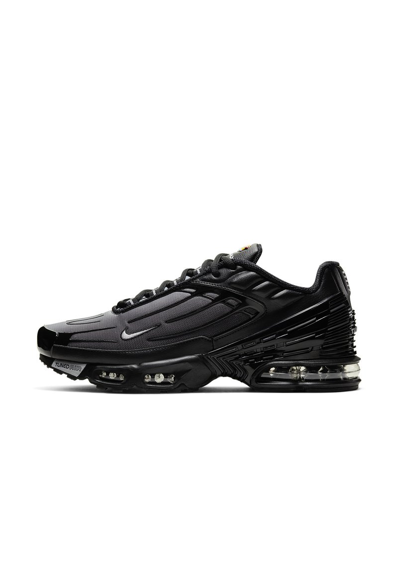 Zapatilla atlética negra con parte superior de tela texturizada, diseño elegante, amortiguación de aire prominente y acentos reflectantes en el talón y los lados.