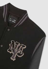 Czarna kurtka varsity z szarymi akcentami, z teksturowanym logo "NY" w jasnoszarym kolorze, ryflowanym kołnierzem z pasiastym detalem oraz zapięciem na napy.