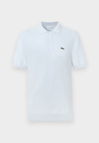Polo bleu clair en coton doux, doté d'un col classique, de deux boutons et d'un petit logo crocodile vert sur la poitrine.