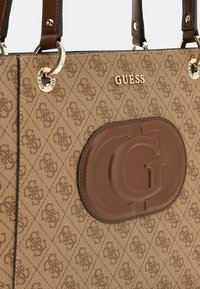 Borsa tote a motivo marrone con dettagli in pelle, caratterizzata da un logo in rilievo ben visibile e hardware dorato sulle maniglie e sulla placca del logo.