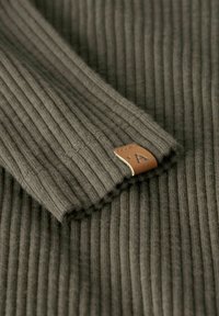 Tessuto a coste verde oliva con una morbida texture, dotato di un'etichetta in pelle marrone con un simbolo. Il design presenta linee verticali prominenti.