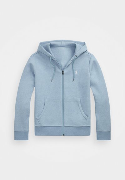 Svetlo modra zadrževalna kapuca, izdelana iz mehkega materiala, z kapuco na vrvico, dvema sprednjima žepoma in majhnim logotipom na prsih.