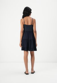 Ναυτικό μπλε καλοκαιρινό φόρεμα με εφαρμοστό φαρδύ κορσέ, ρυθμιζόμενους ιμάντες και φούστα με επίπεδα ριγέ. Κατασκευασμένο από απαλό, ελαφρύ ύφασμα.