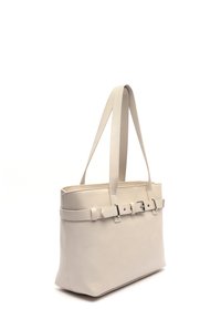 Vaaleanbeige kangaskassi, joka on valmistettu tekstuuri-nahasta, varustettu kahdella tukevalla kahvalla ja koristeellisella vyöyksityiskohdalla, jossa on hopeanväristä metallia.