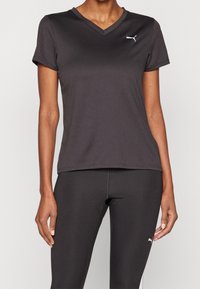 Černé sportovní tričko s krátkým rukávem a výstřihem do V, se bílým logem Puma na levé straně hrudi, vyrobené z hladkého, lehkého materiálu.