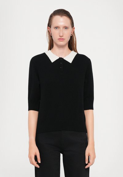 Pull polo noir en tricot à manches courtes, avec un col blanc contrasté et une patte de boutonnage à quatre boutons, texture légèrement côtelée.