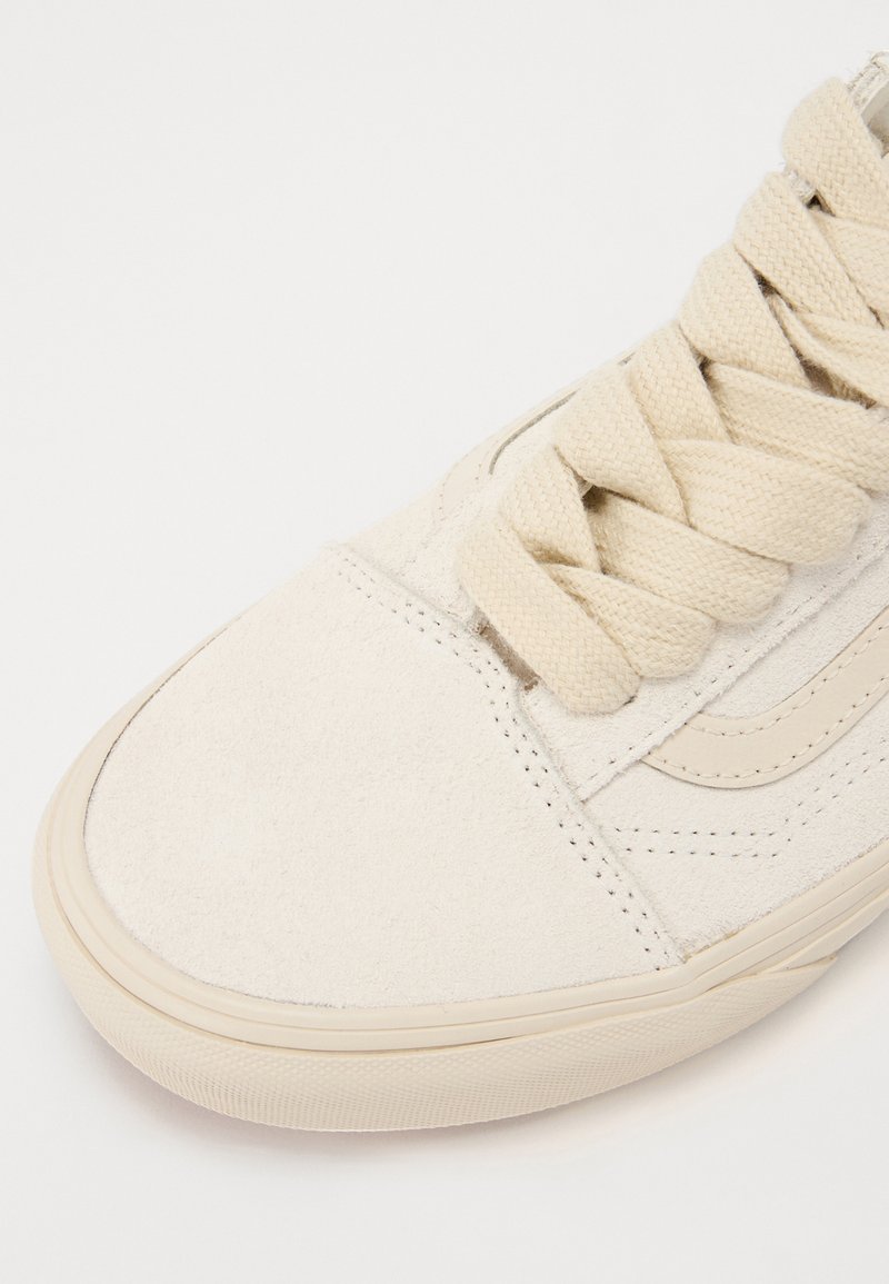 Zapatillas de ante beige con cordones crema, puntera plana y suela de goma texturizada. Presentan un diseño sencillo y una franja lateral en contraste.