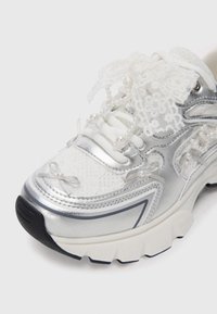 Sølv sneakers med snørebånd og perle detaljer, med en struktureret overdel, tynde hvide snørebånd og en kraftig hvid og sort sål.