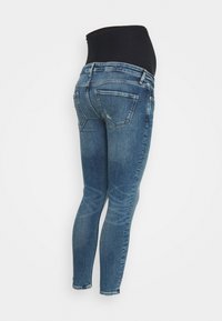 Vaqueros de maternidad con una cinturilla elástica negra alta, con ajuste slim, tejido de denim azul y dos bolsillos traseros.