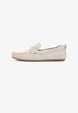 Lichtbeige suède loafer met lage hak, moc-toenaad, klein stoffen logodetail en aantreklus aan de hiel.