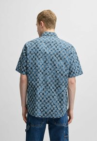 Korte mouw shirt van blauwe stof met een herhalend geometrisch patroon. Met een button-down kraag en een comfortabele pasvorm.