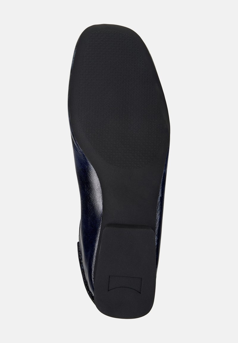 Suola di una scarpa lucida di colore blu navy, con una suola esterna in gomma nera testurizzata e un leggero tacco, esposta su uno sfondo neutro.