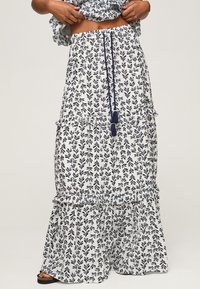 Weiße Maxi-Rock mit einem dunkelblauen Blattmuster, gerafften Stufen und einem Kordelzugbund mit Quasten. Weicher, leichter Stoff.