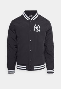 Svart bomberjacka med en vit "NY" logotyp på vänster bröst, med randig ribbad krage, ärmar och nederkant. Tryckknappsstängning.