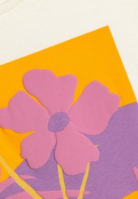 Lyhythihainen, kerma-huokoinen t-paita, jossa on kohokuvioitu vaaleanpunainen kukkasuunnittelu elävän oranssin ja violetin taustan päällä. Sileä puuvillamateriaali.