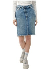 Vaaleansininen farkuhame suoran leikkauksen kanssa, edessä nappikiinnitys ja vyölenkit. Yhdistetty neutraaleihin lenkkareihin ja valkoisiin kuviollisiin sukkiin.