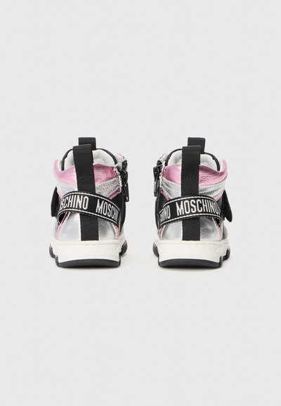 Black and silver sneakers with pink accents, featuring a zip closure, elastic strap, and "Moschino" logo on the strap. Textured materials.