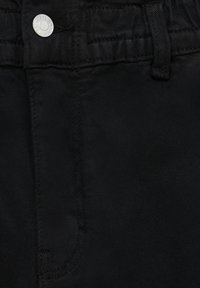 Svarta denimjeans med en slät yta, med en silverfärgad knapp och sydda detaljer längs midjan och fickorna.