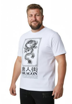 Mężczyzna z brodą, ubrany w białą koszulkę z szczegółową czarną grafiką smoka oraz słowem „DRAGON” wraz z chińskimi znakami.