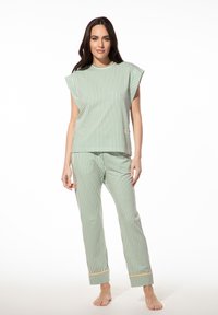 Groen en witte gestreepte pyjama-set met een top met korte mouwen en broek. De top heeft een rechte snit; de broek heeft een gele rand bij de boorden.