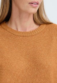 Pullover in maglia bronzo con collo a girocotolo a costine e una texture morbida, che mette in evidenza un colore caldo e uniforme e un semplice dettaglio di design.