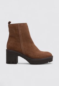 Bottine en suede marron, avec un bout rond, un talon épais à rayures et des détails de couture subtils. Pas de motifs visibles ni d'accents matériels.