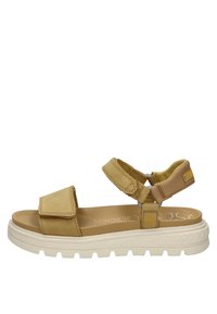 Sandalia beige con correas de Velcro ajustables, plantilla acolchada y una suela blanca gruesa con patrones de agarre texturizados.