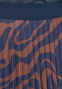 Plisovaná látka s abstraktním vlnitým vzorem v námořnické modré a hnědé barvě a s pevným tmavomodrým pasem.