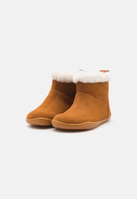 Bottines en daim marron avec doublure en fourrure blanche en haut, design à bout rond et semelle en caoutchouc avec un détail de couture.
