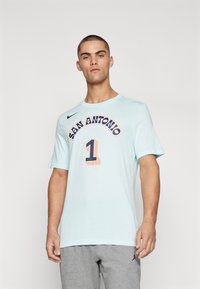 Svetlomodré tričko s krátkymi rukávmi, s nápisom "SAN ANTONIO" a číslom "1" v námorníckej modrej a koralovej farbe, logo Nike na ľavom prsníku.