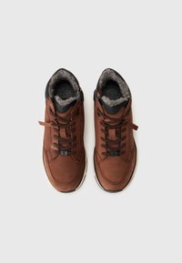 Sneaker in pelle marrone con fodera in pile grigio, dettagli neri e design con lacci. Presenta un colletto imbottito e una suola in gomma testurizzata.