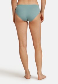 Slip di cotone azzurro chiaro con una consistenza morbida e un elastico in vita, visto da dietro, che mostra un taglio a vita media e un design senza cuciture.