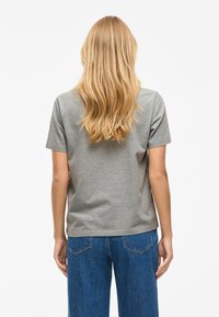 Grå T-shirt med korta ärmar, gjord av mjuk bomull, med en avslappnad passform; bärs med blåa högmidjade denimjeans och visar en avslappnad stil.