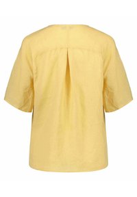 Gelbe Leinenbluse mit kurzen Ärmeln, einem Rückenschlitz und rundem Ausschnitt. Glatte Textur mit entspannter Passform.