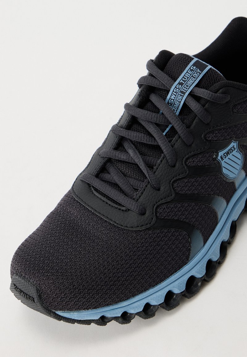Schwarzer Sportschuh mit Mesh-Obermaterial und synthetischen Überzügen. Verfügt über blaue Akzente und eine gepolsterte Sohle mit runden, strukturierten Pods zur Unterstützung.