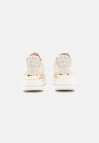 White sneaker with gold accents, textured upper featuring a repeated logo pattern, padded collar, and a thick, cushioned sole.