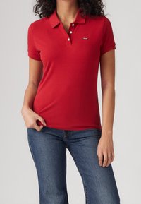Červené polo tričko vyrobené z bavlny, s klasickým límečkem, tříknoflíkovou légou a malým logem Levi's na prsou. Přiléhavý střih.