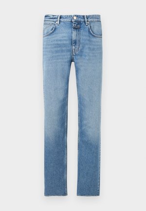 Bijela pamučna majica s podvrnutim rukavima i grafičkim otiskom u sredini sprijeda. Kombinirana sa svijetloplavim trapericama i crnim tenisicama.