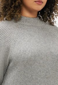 Sweater cinza com nervuras e gola alta, apresentando tecido texturizado e detalhes de costura diagonal nos ombros. Design suave e ajustado.