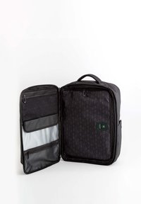 Mochila negra que se abre para mostrar un interior estampado, con bolsillos con cremallera, un compartimento plano y una superficie texturizada.