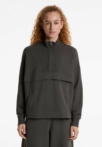 Dunkelgrauer Reißverschluss-Sweatshirt mit hohem Kragen, geripptem Textil, Fronttasche und einem geschichteten Design mit einem horizontalen Paneel an der Vorderseite.
