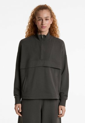 Donkergrijze ritsvest met hoge kraag, geribbelde textuur, voorzak en een gelaagd ontwerp met een horizontaal paneel over de voorkant.