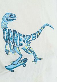Grafik zeigt einen blauen Dinosaurier mit kunstvollen Mustern auf einem Skateboard, vor einem strukturierten weißen Hintergrund. Der Text lautet "WAGE ES, DU ZU SEIN."